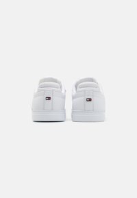 Białe sneakersy z gładkiej skórzanej cholewki, wyściełanym kołnierzem i kontrastowym logo na pięcie. Okrąły nosek i gumowa podeszwa.