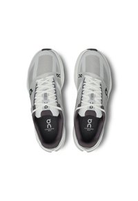 Baskets de sport grises et blanches avec un tissu en maille, design à bout rond, accents sombres contrastants et logo de marque bien visible sur le côté.