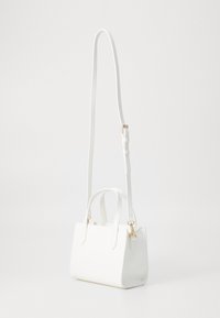 Borsa bianca realizzata in pelle liscia con una forma strutturata, manici corti e una tracolla lunga rimovibile. Presenta dettagli in metallo dorato.