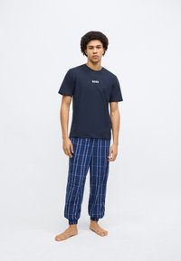 Tricou bleumarin din bumbac cu logo-ul "BOSS", asortat cu pantaloni de pijama albaștri cu model în carouri, având manșete elastice și croială lejeră.