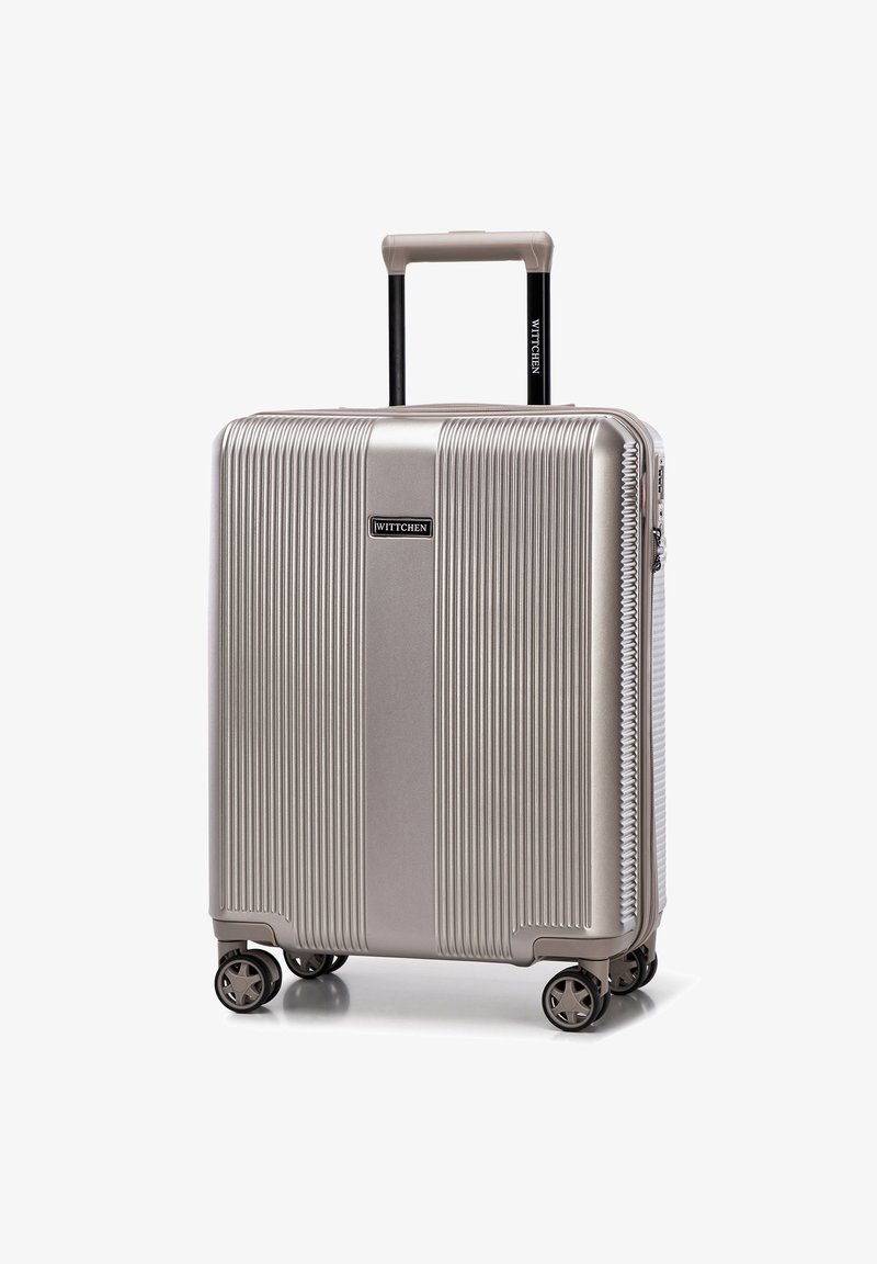 Stříbrný tvrdý kufr s vertikálními drážkami, teleskopickou rukojetí a otáčivými kolečky. Logo značky je viditelně zobrazeno.