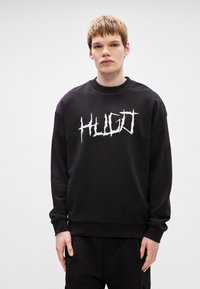 Μαύρη μπλούζα crewneck από μαλακό �ύφασμα με λευκό καλλιτεχνικό λογότυπο "HUGO" μπροστά στο στήθος; ίσια γραμμή με ριμπ μανσέτες και στρίφωμα.