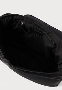 Εσωτερικό μαύρης υφασμάτινης τσάντας με λεία υφή και θήκη με φερμουάρ, διαθέτοντας απλό σχεδιασμό χωρίς ορατά μοτίβα ή μεταλλικά στοιχεία.