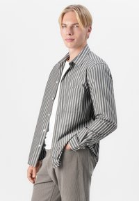 Striped shirt in gray and white fabric with button-down collar, single chest pocket, long sleeves, and relaxed fit.
