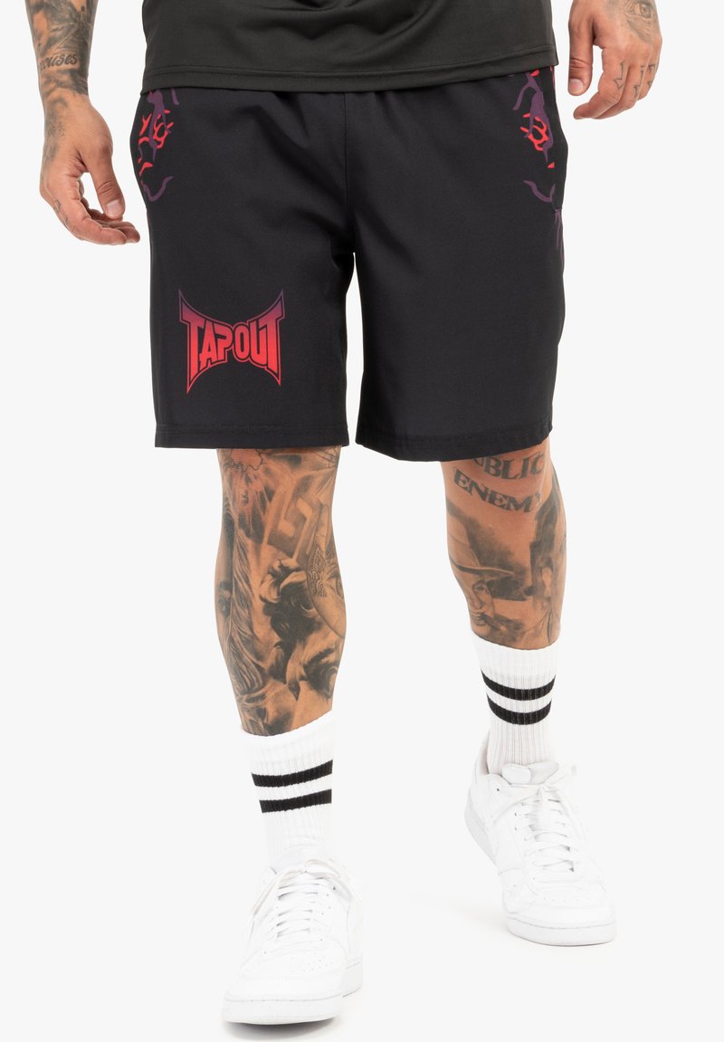 Sorte sportsshorts med et rødt "TAPOUT"-logo, udstyret med lilla accentdesigns. Bæret med hvide sokker og sneakers. Glat stofstruktur.