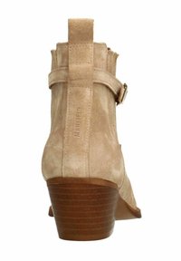 Stivale alla caviglia in suede beige con tacco basso impilato, cinturino laterale e zip posteriore. Presenta il logo del marchio impresso sul tallone.