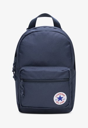 Marineblå ryggsekk med strukturert finish, avrundet form, frontlomme med glidelås og en rund "Converse All Star"-lapp på nedre front.