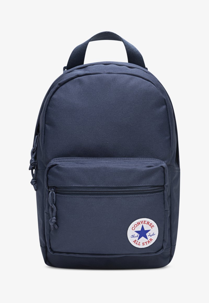 Σακίδιο πλάτης σε ναυτικό μπλε με υφή, στρογγυλεμένο σχήμα, εμπρόσθια τσέπη με φερμουάρ και κυκλικό λογότυπο "Converse All Star" στο κάτω εμπρόσθιο μέρος.
