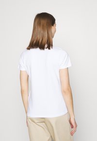 T-shirt en coton blanc à manches courtes, design simple à col rond, texture lisse et ourlet inférieur droit, vu de l'arrière.