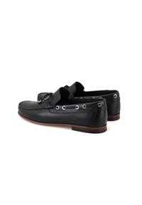 Schwarze Lederloafers mit einer gestickten Detail um die Kante, Ösenakzenten und einem niedrigen braunen Absatz. Glatte Textur, klassisches Design.