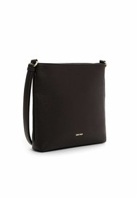 Mustast tekstureeritud nahast risti kantav kott kuldse logoga ja reguleeritava rihmaga, valgel taustal.