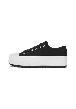 Black low-top canvas sneaker with thick white platform sole and white rubber toe cap, viewed from the side on a white background.