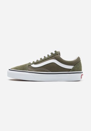 Niskie oliwkowo-zielone sneakersy z białym paskiem po boku, białymi sznurowadłami i grubą białą podeszwą z czarną obwódką, widziane z zewnątrz.