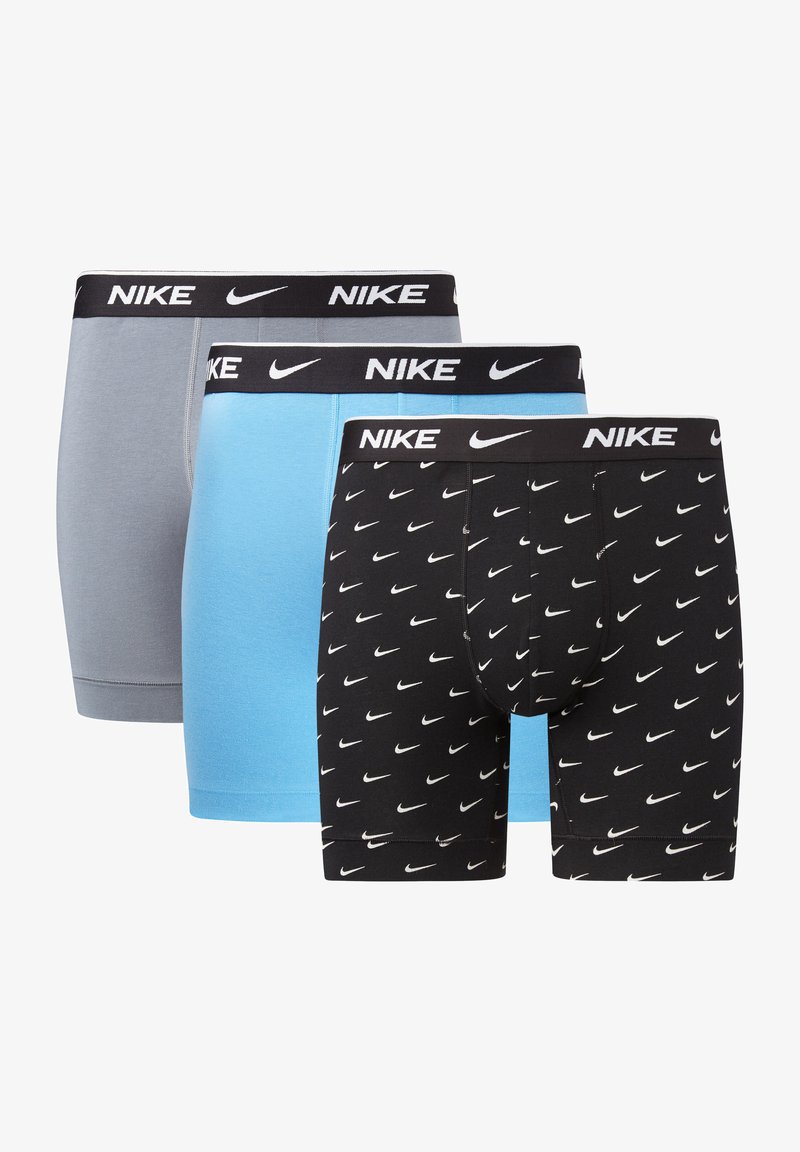 Três pares de boxers Nike: cinza, azul claro e preto com padrões de swoosh brancos. As faixas elásticas na cintura apresentam uma ousada marcação da Nike.