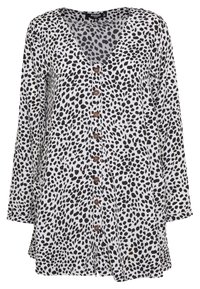 Blůza s leopardím vzorem, zapínání na knoflíky, vyrobena z lehkého materiálu. Má výstřih do V, dlouhé rukávy a hnědé knoflíky vpředu. Spodní lem je vzadu mírně delší.