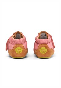 Scarpe per bambini morbide in rosa e marrone con dettagli in suede, suola piatta, strap in velcro e suola in gomma verde. Logo visibile sui talloni.