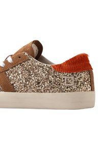 Sneaker bassa in suede marrone, lati con glitter dorato, lacci bianchi, suola avorio e linguetta sul tallone arancione con texture.