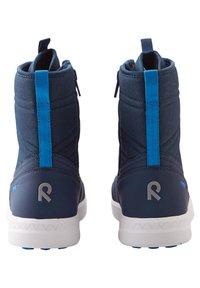 Botas de tobillo azul marino con una textura suave, que cuentan con una lengüeta de tiro en un azul contrastante, una suela blanca y un sutil logotipo en el talón.