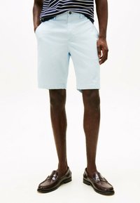 Pantaloni corti blu chiaro in un tessuto morbido e liscio con un taglio dritto. Tasche su entrambi i lati, abbinati a mocassini marrone scuro.