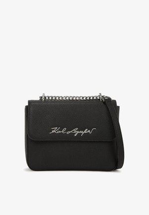 Juodas odinis per petį nešiojamas krepšys su tekstūruotu paviršiumi, su sidabriniu grandininiu dirželiu ir išraižytu logotipo detalė ant priekio.