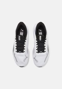 Weiße Sportschuhe mit schwarzen Akzenten, Obermaterial aus Mesh, gepolsterte Zunge, schwarze Schnürsenkel und Logodetails an den Seiten und der Zunge.
