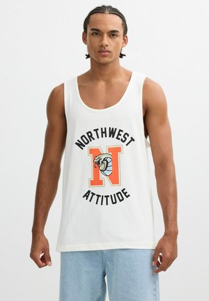 Joven con cabello trenzado, vestido con una camiseta sin mangas blanca con una "N" naranja y un logo de serpiente, y texto "Northwest Attitude", combinado con jeans azul claro.
