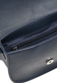 Interno di una borsa in pelle blu navy con una finitura testurizzata, dotata di tasca con zip e hardware in argento. Fodera liscia completa il design.