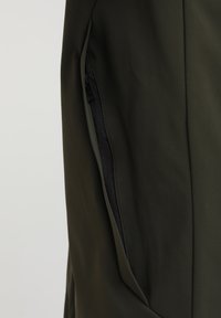 Giacca verde oliva con una tasca laterale con zip sicura, texture morbida e design affusolato con silhouette su misura.
