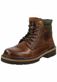 Botas de cuero marrón con cordones y un acabado texturizado, puño de punto verde y suela de goma negra. Presenta ojales de metal y costuras decorativas.