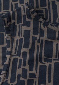 Navy fabric featuring geometric beige pattern. Close-up of soft texture, with a crew neckline and visible stitching details.