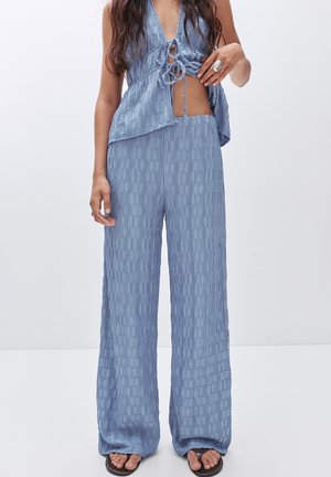 Lichtblauw, textuur vol twee-delige outfit met een cropped top met strikdetail en wijde broek met een geometrisch patroon.
