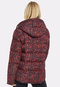 Rød og sort leopardmønstret puffjakke med hætte, med et quiltet design og elastiske manchetter, set fra ryggen.