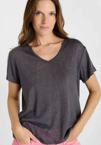 Donkergrijs v-hals T-shirt met korte mouwen en een lichte textuur. Heeft een ontspannen pasvorm en een subtiele logo-accent aan de zoom.