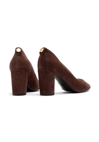 Brązowe zamszowe szpilki z zaokrąglonym noskiem, masywnym obcasem i złotym akcentem na tylnym obszarze obcasa. Gładka tekstura.