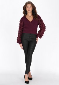 Viininpunainen kietaisupaita, jossa on teksturoidut, kerrokselliset hihat; yhdistetty istuviin mustiin housuihin ja mustiin korkokenkiin; sileä kangas.