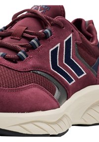 Burgunderfarbene Sportschuh mit einem Obermaterial aus Mesh und Wildleder, marineblauen Akzenten, integriertem Schnürsystem und einer klobigen, cremefarbenen Sohle.