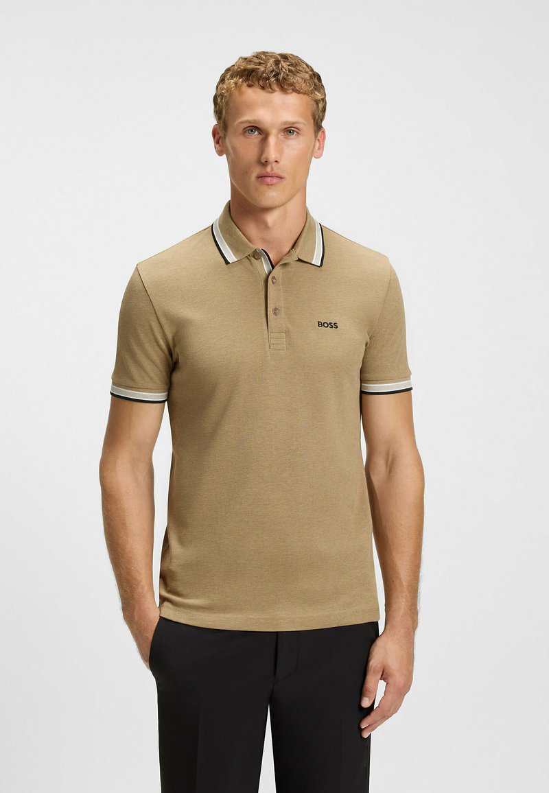 Beiger Poloshirt mit kurzen Ärmeln, kontrastierendem schwarz-weiß gestreiftem Kragen und Ärmelbündchen, besticktem Logo auf der Brust und glatter Textur.