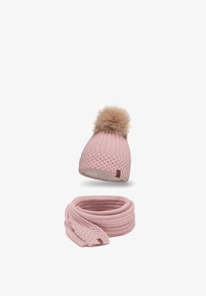 Cappello lavorato a maglia rosa con pom-pom in pelliccia e sciarpa coordinata. Entrambi presentano un motivo testurizzato e un piccolo etichetta marrone sul cappello.