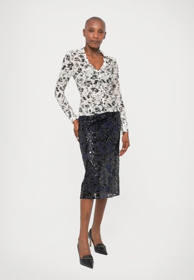 Floral-patterned long-sleeve blouse in white and black, paired with a navy sequin pencil skirt, complemented by pointed black heels.