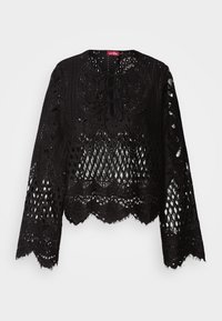 Blouse noire en dentelle à manches longues avec motifs floraux, bords festonnés et détail à lacets au niveau du décolleté.