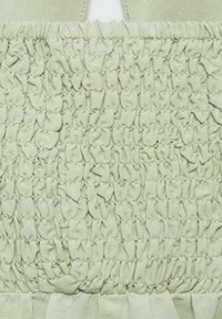 Tissu smocké vert clair avec une texture froncée, présentant des rangées horizontales de plis et une zone lisse et non texturée au-dessus.