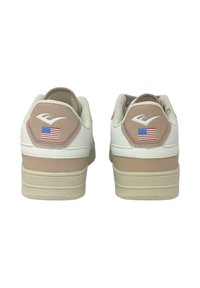 Sneaker bianchi e beige con tomaia in pelle texturizzata, dotate di una toppa sul tallone esagonale e un piccolo dettaglio con la bandiera americana.