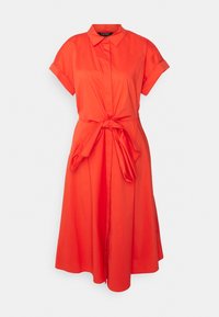 Ljus orange kortärmad skjortklänning med krage, knapprad fram och knytbart midjebälte, visad på en enkel vit bakgrund.