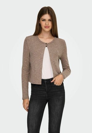 Lichtbruine geribde cardigan met een ronde hals, enkele knoopsluiting en lange mouwen, gedragen over een witte top en zwarte jeans.