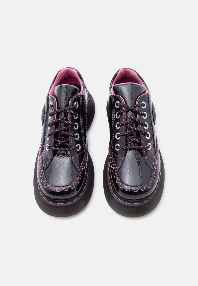 Zwarte sleehak schoenen van lakleer met roze stiksel, roze en zwarte veters, en roze binnenvoering, gezien van bovenaf tegen een witte achtergrond.