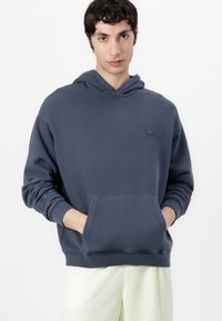 Felpa blu navy realizzata in materiale morbido, con tasca frontale a marsupio, cappuccio con cordoncino e piccolo logo sul petto.
