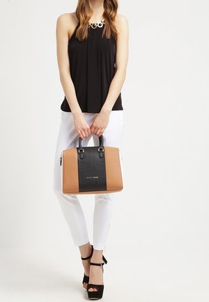 Structured handbag in black and tan, featuring a smooth texture and sleek design. Equipped with dual top handles and zipper accents.