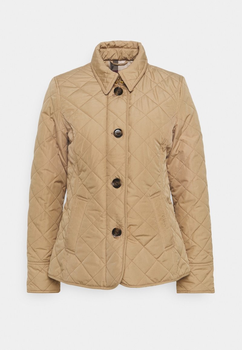 Veste matelassée beige avec col, quatre boutons sur le devant, poches latérales et motifs de surpiqûres subtils. Tissu texturé et léger.