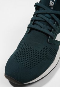 Dark teal sneaker featuring a breathable mesh upper, textured pattern, and traditional lace-up design with a white sole accent.