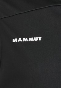 Zwarte stoffen shirt met een gladde textuur, korte mouwen en een wit "MAMMUT" logo op de voorkant bedrukt.